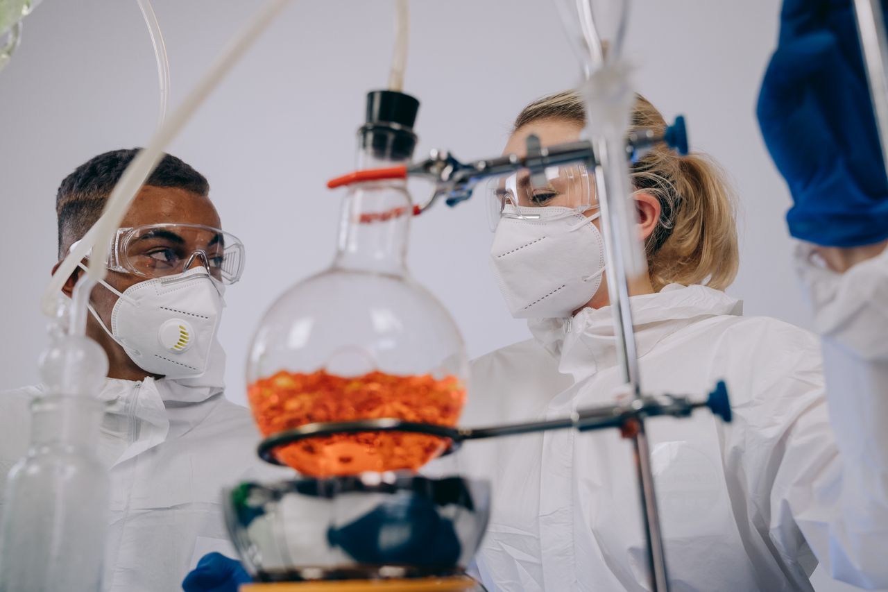 services-04 Two scientists in PPE conducting experiments with lab equipment, focusing on chemical reactions.